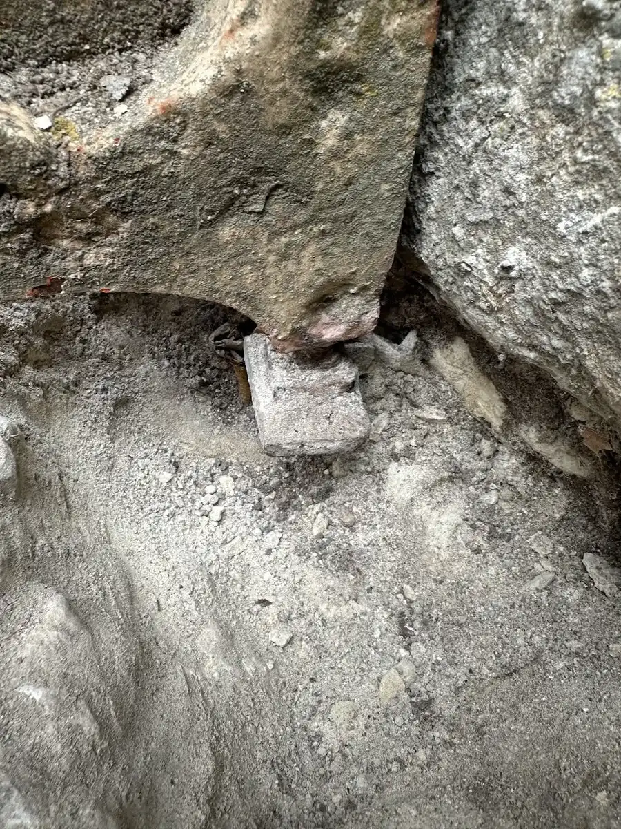 Ancien pivot rouillé scellé dans la pierre du pilier